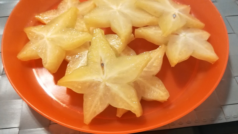 橙色の皿に盛られた星形輪切りカットのスターフルーツ